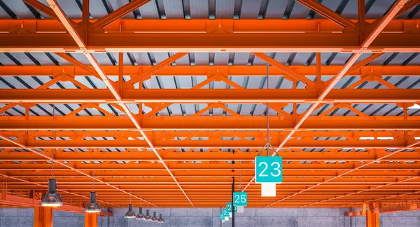 Innenraum Einer Lagerhalle Mit Auffälligen Orangefarbenen Stahlträgern Und Nummerierten Bahnhofsschildern Stockbild