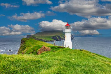 Beyaz deniz feneri yeşil çimen tarlası Faroe adası bulutlu gökyüzü