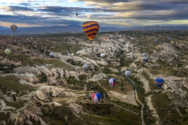 GOREME / TURKEY - 26 Haziran 2022: Kayalık manzara kapsülü üzerinde uçan renkli sıcak hava balonları