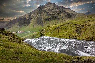 Skogafoss nehri bir dağla yeşil bir vadiden akıyor. İzlanda