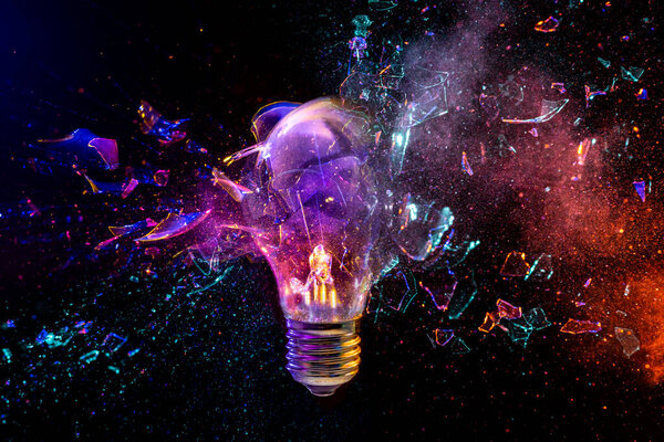Light bulb is exploding while emitting colorful powder on a black background