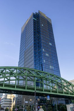 Modern cam ofis kulesi yeşil tren köprüsü Tokyo Japonya 'nın üzerinde yükseliyor.