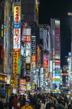 Shinjuku 'da, Tokyo' da, neon ışıklı Japonya 'da geceleri kalabalık içinde yürüyen turistler.