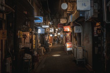 Tokyo 'da gece dar bir sokakta restoranlar ve barlar görünüyor. 