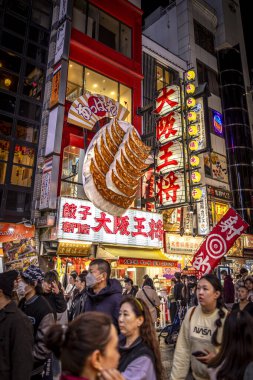 Dotonbori 'de turistler, Gyoza restoranının tabelasının altında osaka gecesi.