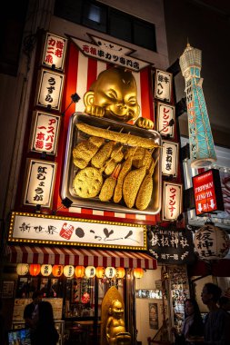 Altın bebek Shinsekai 'de kushikatsu şişleri tutuyor, osaka