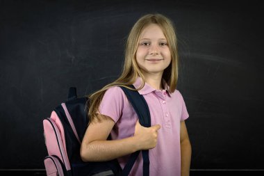 Sırt çantası takmış gülümseyen okul kızı.