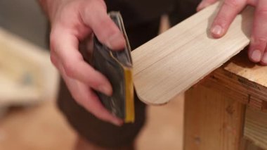 Marangoz zımpara kağıdıyla tahta zımparalıyor.