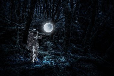 Keşfedilmemiş bir gezegende yürüyen astronot. Karışık ortam