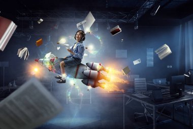 Roketin üstünde kulaklık takan bir çocuk. Karışık ortam