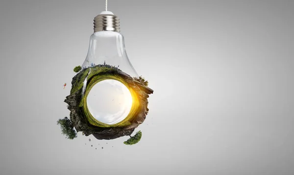 Green landscape inside light bulb. Mixed media