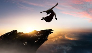 Gün batımına ve bulutlara karşı kadın dansçı. Karışık ortam