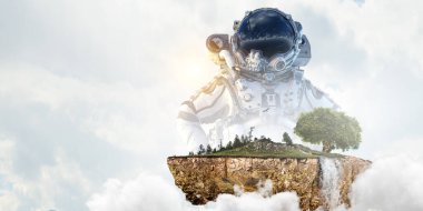 Bulutlu arka plan ve yeşil ağaca karşı astronot. Karışık ortam