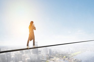 İp üzerinde dengede duran bir iş kadını resmi. Risk kavramı. Karışık ortam