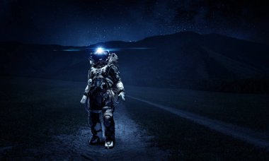 Keşfedilmemiş bir gezegende yürüyen astronot. Karışık ortam