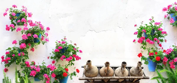 ステュクコの壁にゼラニウムと古いピッチャーと植木鉢付きの水平バナー 白い壁にゼラニウムと粘土ワイン瓶のポット 村の家の伝統的な地中海の壁の装飾 — ストック写真