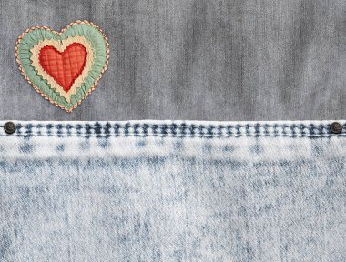 Gri ve açık gri arka plan, dikişli ve hissedilmiş bir kalp. Açık gri kot pantolon kumaş desenli. Sevgililer günü kot arka planı. Metin için alanı kopyala