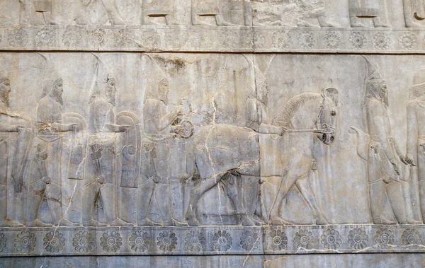 Ancient wall with bas-relief with assyrian foreign ambassadors with gifts and donations, Persepolis, Iran. UNESCO world heritage site