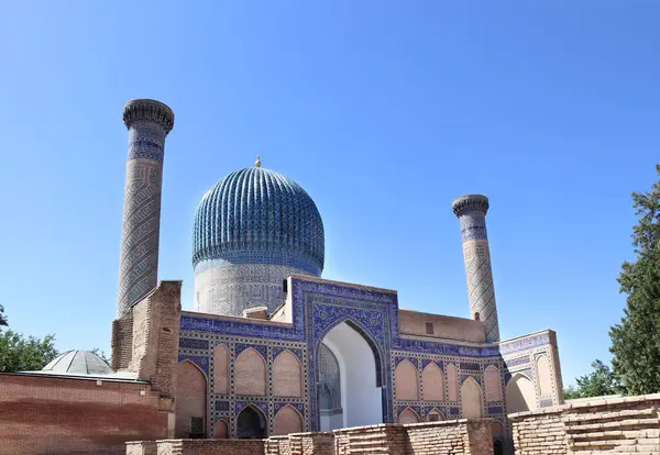 stock image Famous landmark Gur Emir Mausoleum in Samarkand, Uzbekistan. Exterior of tomb of Amir Timur Tamerlan. Mosaic arch entrance, minarets and dome of Gur-e-Amir mausoleum of turco-mongol conqueror Timur