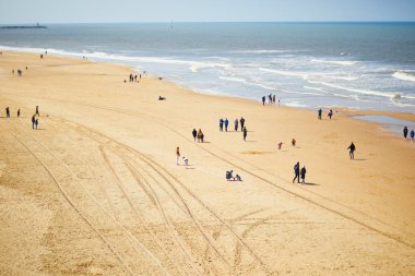 HAGUE, NETHERLANDS - 28 Nisan 2022: Scheveningen, Lahey, Hollanda 'da sahilde yürüyüş yapmaktan keyif alan insanlar