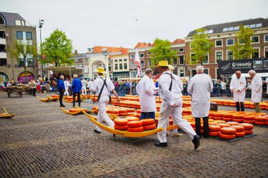 ALKMAAR, NETHERLANDS - 29 Nisan 2022: Hollanda 'nın Alkmaar kentindeki ünlü Hollanda peynir pazarında peynirle yürüyen peynir taşıyıcılar