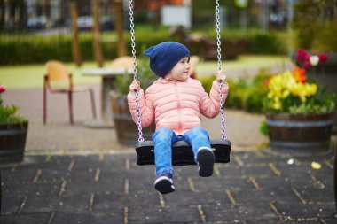 Salıncakla oyun parkında oynayan 4 yaşındaki mutlu kız. Çocuklar için açık hava aktiviteleri