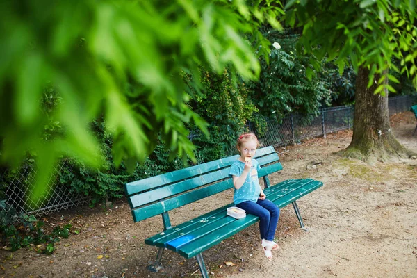 お弁当を持ってベンチに座って夏の日にピクニックをしている愛らしい女の子 公園で健康的な軽食を楽しんでいる子供 小さな子供のための屋外夏の活動 — ストック写真