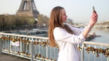 Paris, Fransa 'da Eyfel kulesinin yanında akıllı telefonuyla selfie çeken bir kız. Fransa 'da tatil yapan bir turist. Genç kadın video blogu kaydediyor