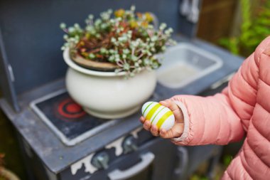 Colored Easter eggs hidden in flower pots for the Easter tradition of egg hunt. Fun Easter activities for kids