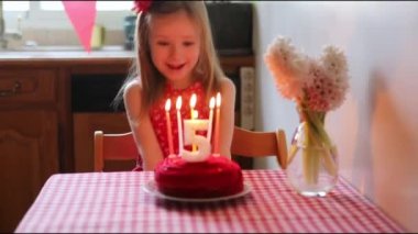 Happy little girl celebrating her fifth birthday and making a wish. Little kid with birthday cake and candle