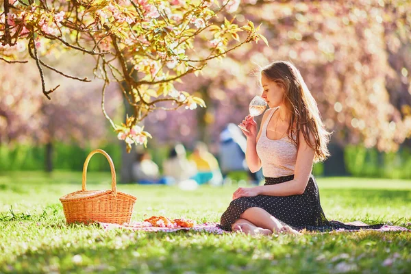 桜の季節に公園で晴れた春の日にピクニックをしている美しい若い女性 フランス パリ近郊の有名なスコー公園の若い女性 — ストック写真