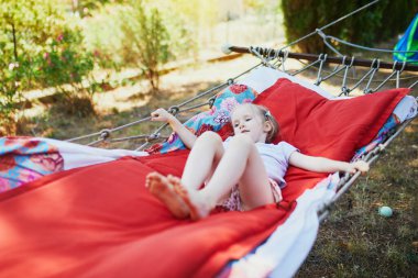 Adorable preschooler girl resting in hammock outdoors. Outdoor summer activities for kids