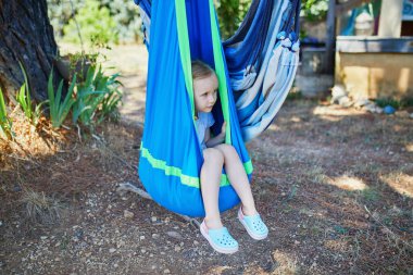 Sevimli anaokulu kızı dışarıda hamakta dinleniyor. Çocuklar için açık hava yaz aktiviteleri