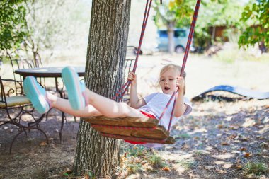 Salıncakta sallanan 4 yaşındaki kızın kutlu olsun. Oyun bahçesinde tahterevallide sallanan mutlu çocuk. Çocuklar için açık hava yaz etkinlikleri