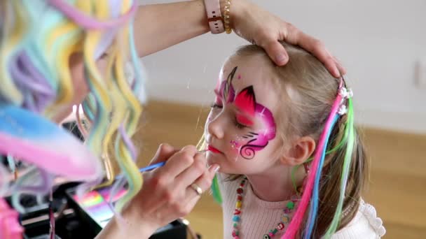 子供は絵を描く アーティストは誕生日パーティーでユニコーンのような小さな未就学児の女の子を描いています 子供のための創造的な活動 — ストック動画
