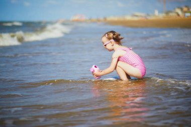 Preschooler girl playing on the sand beach at Atlantic coast of Normandy, France. Outdoor summer activities for kids