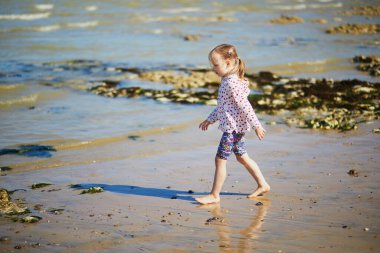 Preschooler girl having fun on the sand beach at Atlantic coast of Normandy, France. Outdoor summer activities for kids