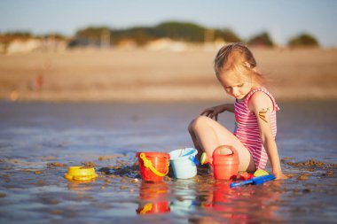 Preschooler girl playing on the sand beach at Atlantic coast of Normandy, France. Outdoor summer activities for kids