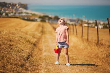 Preschooler girl going to the beach at Atlantic coast of Normandy, France. Outdoor summer activities for kids