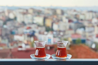 İstanbul, Türkiye 'nin Asya yakasındaki Uskudar ilçesinin çatıları manzaralı sıcak siyah çay dolu bir lale şeklinde iki Türk bardağı