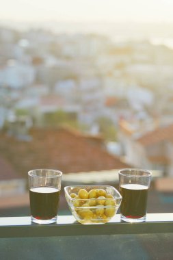 İstanbul, Türkiye 'nin Asya yakasında Uskudar ilçesinin çatıları manzaralı iki kadeh kırmızı şarap ve yeşil zeytin.