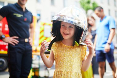 Sevimli anaokulu kızı itfaiyeci gibi davranıyor ve koruyucu bir kask takıyor.