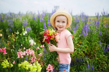 Çiftlikten güzel antirrhinum çiçekleri toplayan sevimli bir kız. Küçük çocuklar için açık hava yaz aktiviteleri