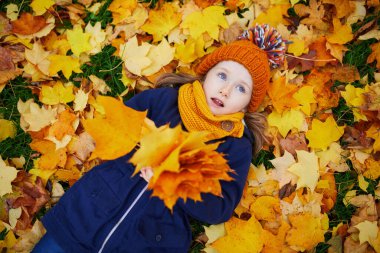 Sevimli anaokulu kızı dışarıda güneşli ve güzel bir sonbahar gününün tadını çıkarıyor. Fransa 'nın Paris şehrinde yerde yatan mutlu çocuk. Çocuklar için açık hava sonbahar aktiviteleri
