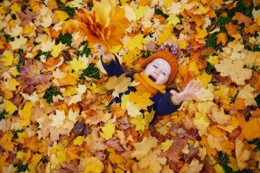 Sevimli anaokulu kızı dışarıda güneşli ve güzel bir sonbahar gününün tadını çıkarıyor. Fransa 'nın Paris şehrinde yerde yatan mutlu çocuk. Çocuklar için açık hava sonbahar aktiviteleri