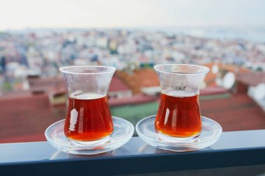 İstanbul, Türkiye 'nin Asya yakasındaki Uskudar ilçesinin çatıları manzaralı sıcak siyah çay dolu bir lale şeklinde iki Türk bardağı