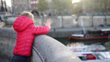 Paris, Fransa 'da Seine nehrinde seyir halindeki gezinti teknesinde turistlere el sallayan sevimli anaokulu kızı.