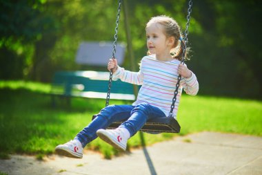 Salıncakta sallanan 5 yaşındaki mutlu kız. Oyun bahçesinde tahterevallide sallanan mutlu çocuk. Çocuklar için açık hava yaz etkinlikleri