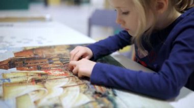 Bulmaca oynayan sevimli anaokulu kızı. Yapboz parçalarını birleştiren çocuk. Çocuk yapboz yapıyor. Eğlenceli aile eğlencesi..