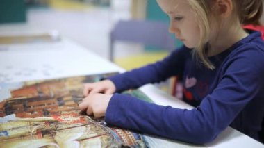 Bulmaca oynayan sevimli anaokulu kızı. Yapboz parçalarını birleştiren çocuk. Çocuk yapboz yapıyor. Eğlenceli aile eğlencesi..